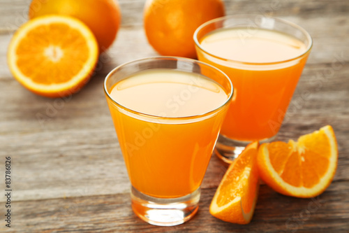 Glass of fresh orange juice on wooden background