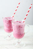 Pomegranate smoothie in glass on white wooden background
