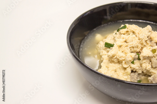 Fried Eggs in Clear Soup in black bowl on white background