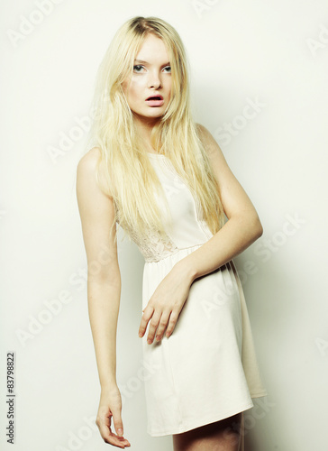  fashion blond woman in white dress posing in studio