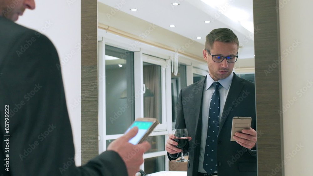 Businessman drinking wine and texting on smartphone
Businessman drinking wine and texting on smartphone