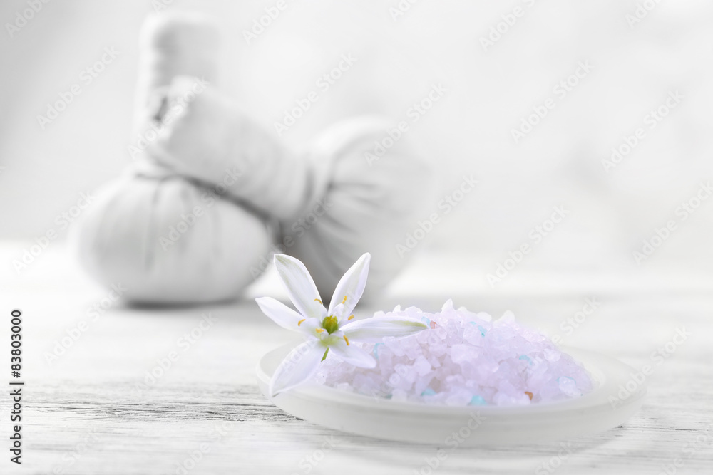 Sea salt, flowers and spa treatment on color wooden table, on light background Sea salt, flowers and spa treatment on color wooden table, on light background