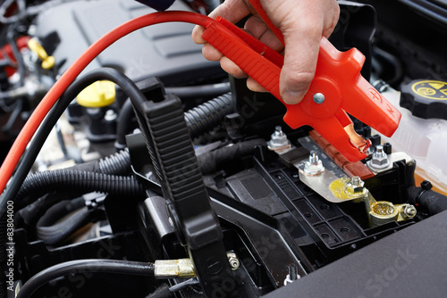 Close-Up Of Mechanic Attaching Jumper Cables To Car Battery