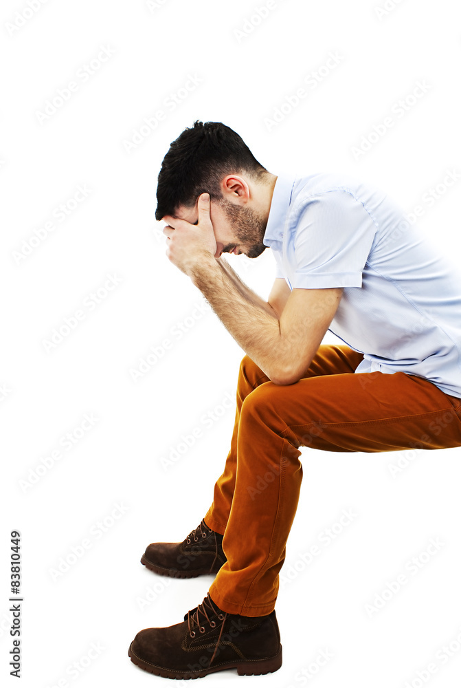 Young casual man sitting disappointed with his face in his hands Young casual man sitting disappointed with his face in his hands