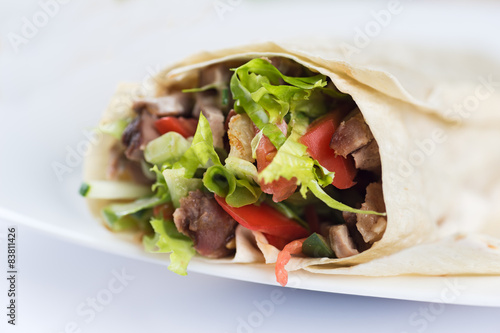 Tortilla with a delicious grilled meat and fresh mixed leafy gre