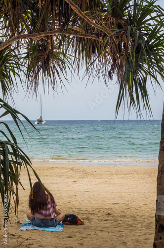 Pretty girl enjoys the beautiful Patong Beach shaded by a tree
