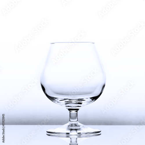 An empty cognac snifter in slightly blue light with a reflection