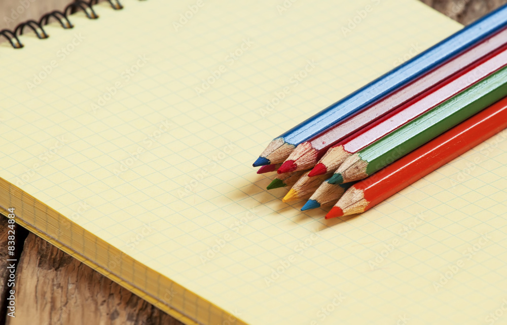 Obraz premium Workspace with colored pencils and notebook on old wooden table