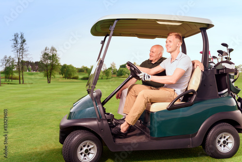 Side view of two golfer driving cart
