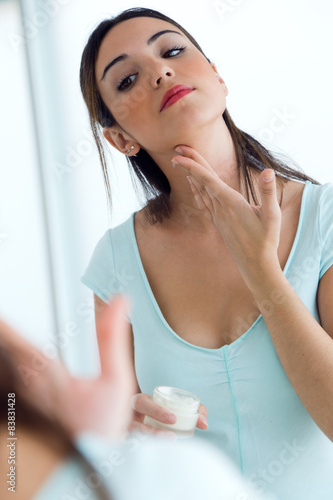 Young woman caring of her skin standing near mirror in the bathr