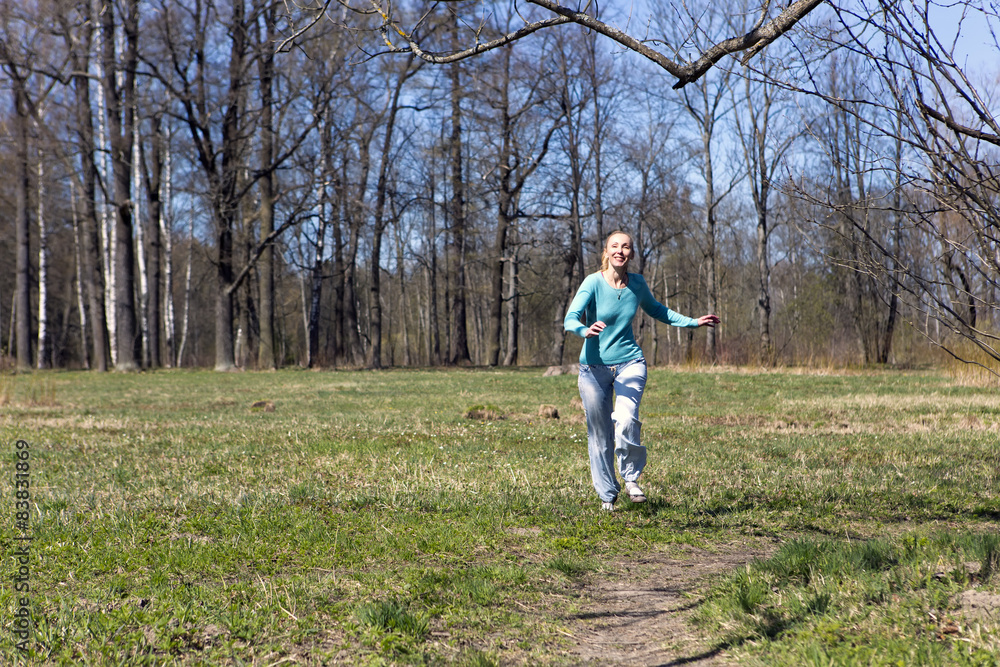 The woman runs on the track in the spring wood The woman runs on the track in the spring wood
