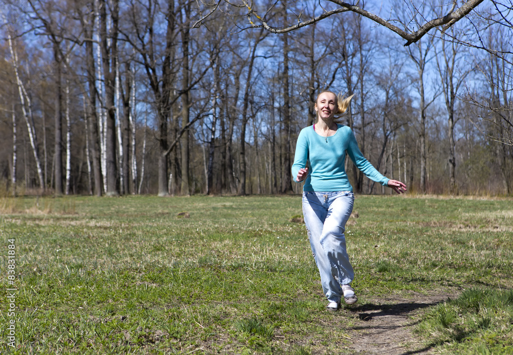 The woman runs on the track in the spring wood