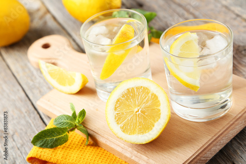 Fresh lemonade with lemon on grey wooden background