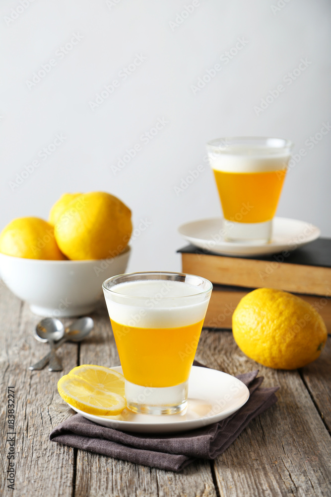 Tasty lemon jelly in glass on grey wooden background Tasty lemon jelly in glass on grey wooden background