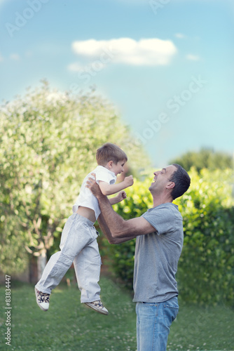 Father throwing son in the air and playing in the park.