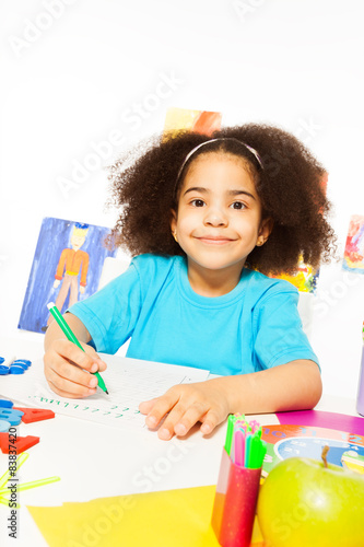 Cute African girl writing letters with pencil