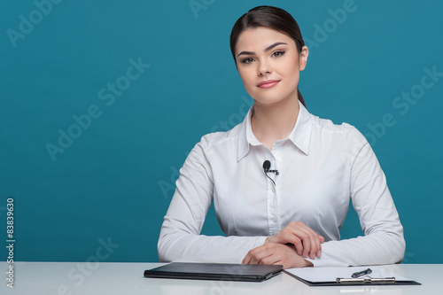 Beautiful girl tv newscaster is reporting sitting at the table photo