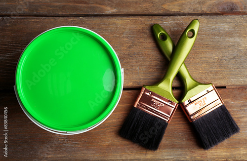 Paint can and paint brushes on wooden background photo