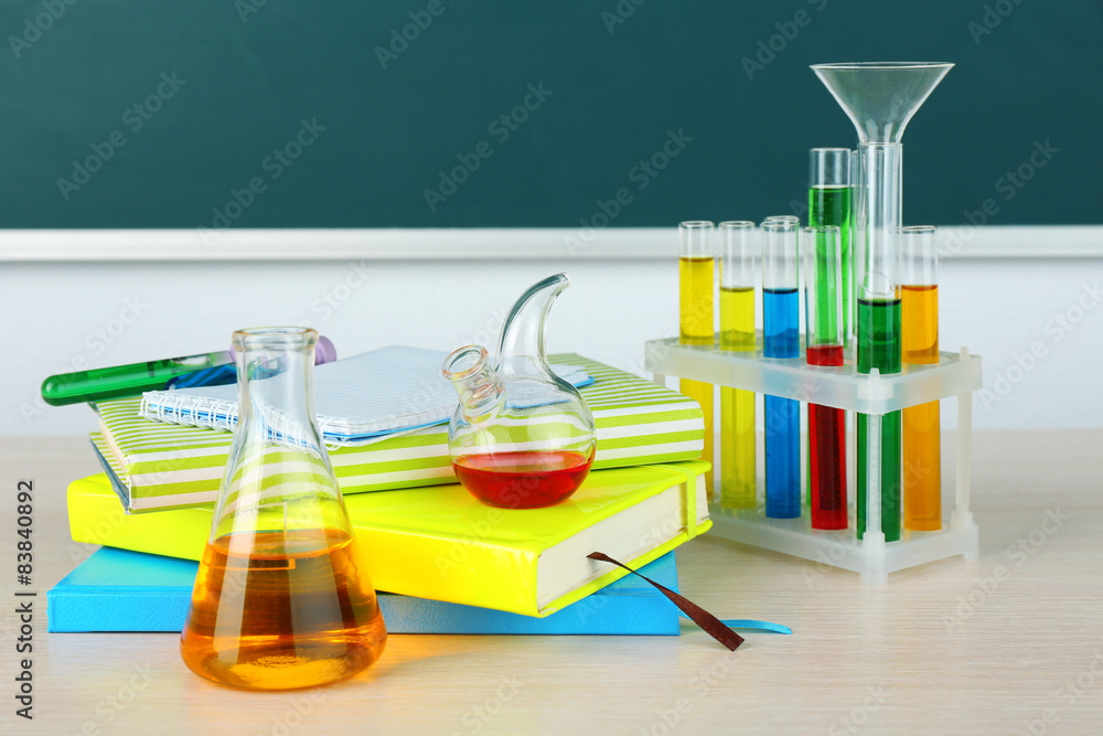 Desk in chemistry class with test tubes on green blackboard background Desk in chemistry class with test tubes on green blackboard background