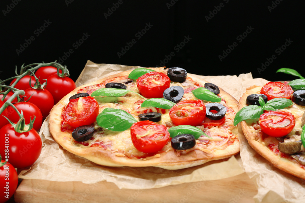 Tasty pizza with vegetables and basil on black background