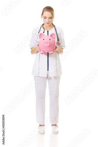 Young female doctor holding a piggybank. photo