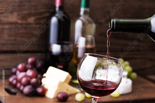 Obraz na plátně Red wine pouring into glass, close-up.