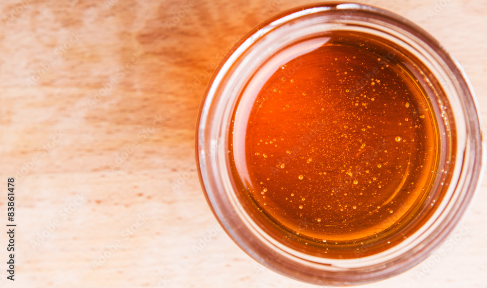Honey in a mason jar on a wooden background Honey in a mason jar on a wooden background
