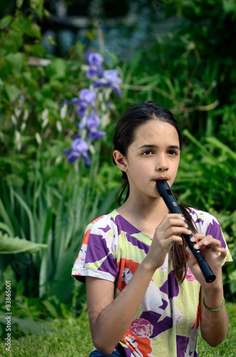 Little Hispanic Girl Plays the Recorder in a Garden