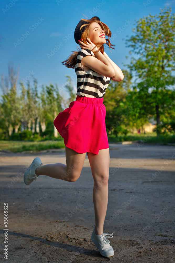 Girl running holding a hat.