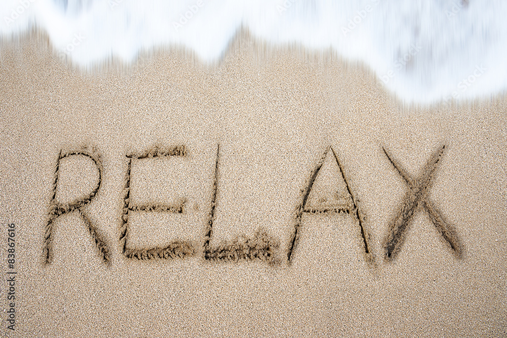 Fototapeta premium Relax word handwritten in sand on beach