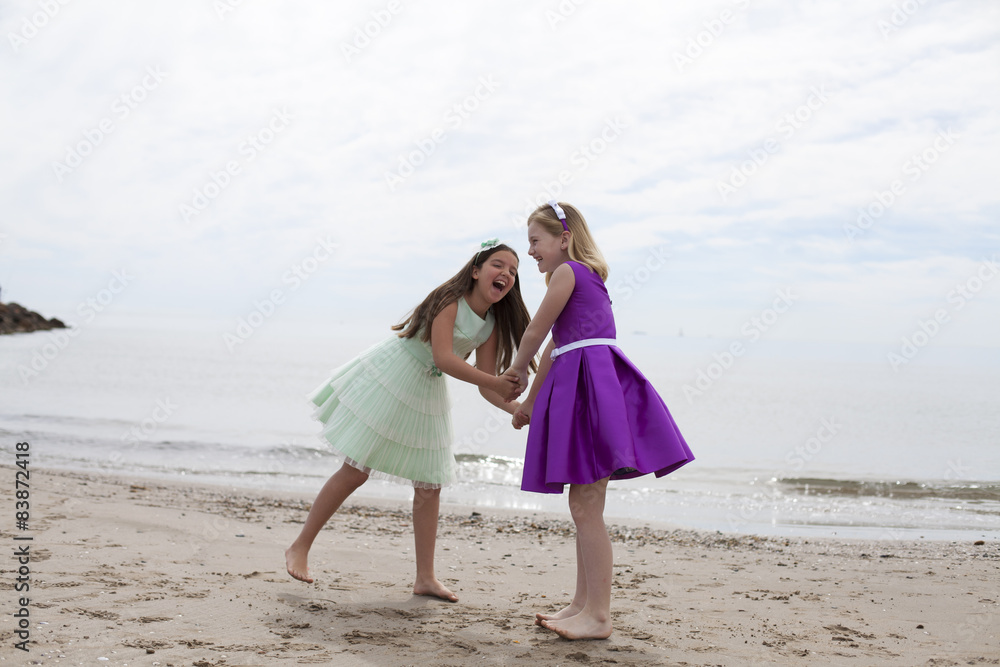 Niñas con vestidos de fiesta jugando y riendo en la playa Niñas con vestidos de fiesta jugando y riendo en la playa