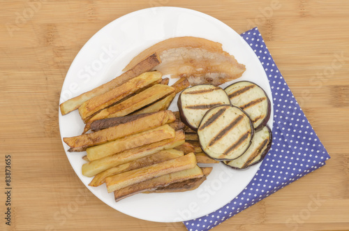 Fries potatoes with grilled eggplant on wooden background