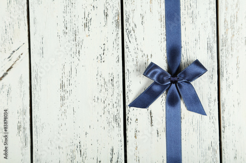 Blue ribbon with bow on white wooden background