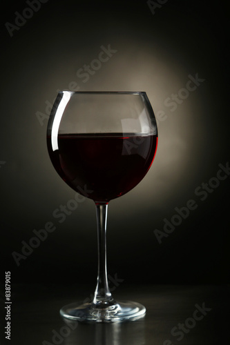 Red wine glass with bottle on black background