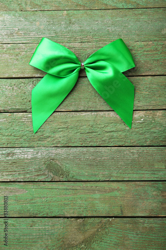 Green bow on green wooden background