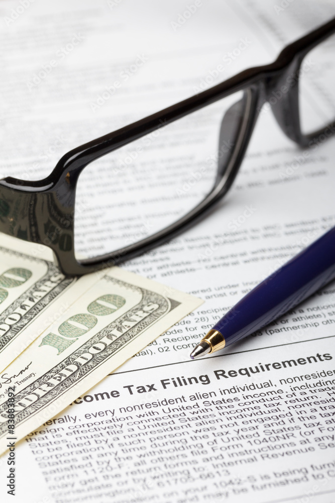 Tax form with pen for fill, dollar bills and glasses Tax form with pen for fill, dollar bills and glasses