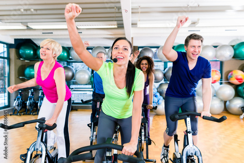 Group of men and women spinning on fitness bikes in gym