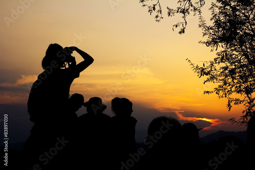 Silhouette of travelers with camera during sunset