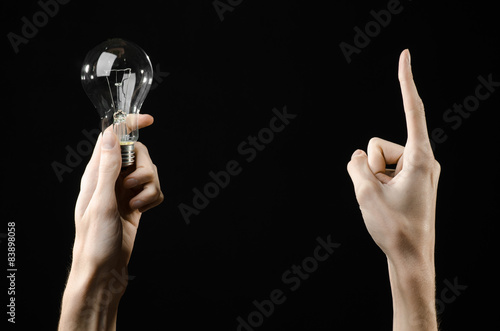 human hand holding a light bulb on black background in studio