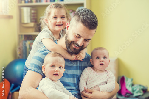 Young hipster father hugging his cute little daughters