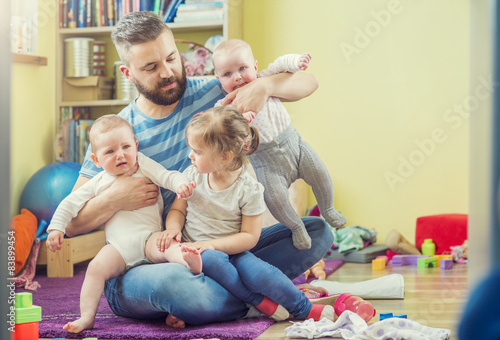 Young hipster father hugging his cute little daughters