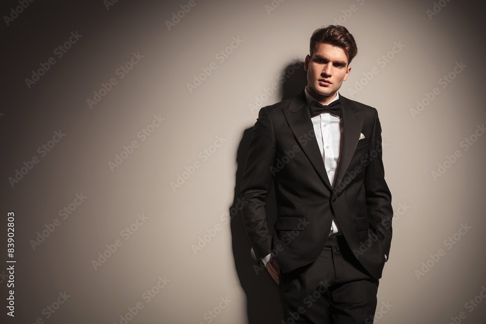 Elegant young business man leaning on a grey wall Elegant young business man leaning on a grey wall