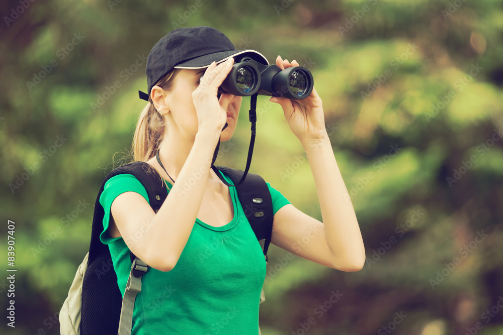 Hiker looking through binoculars in forest Hiker looking through binoculars in forest