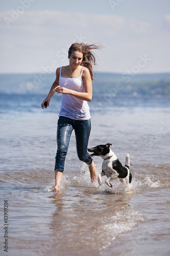 Girl and dog running on a beach © Beznika