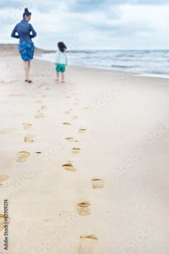 Footprints of mother and daughter walking on the beach 