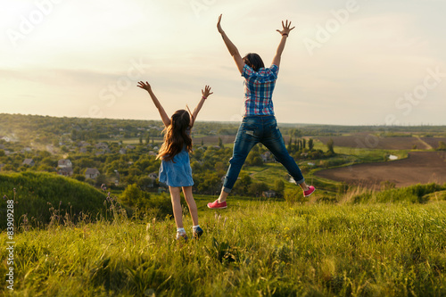 mother and daughter leap at sunset