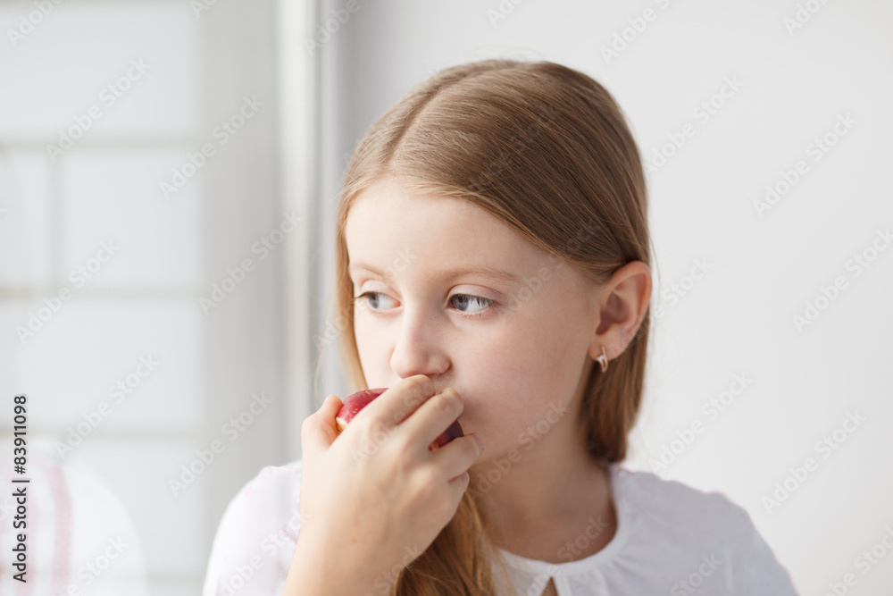 Little girl looking out the window and eating apple Little girl looking out the window and eating apple