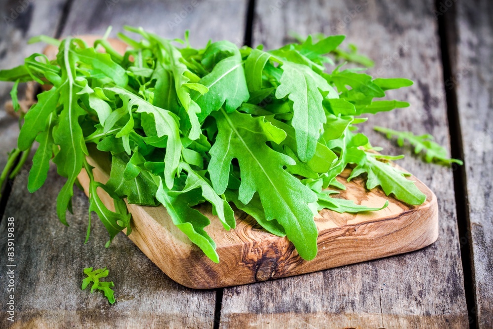 Fresh organic arugula on cutting board Fresh organic arugula on cutting board