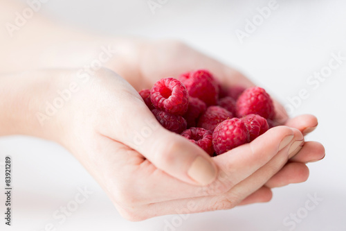 close up of woman hands holding raspberries