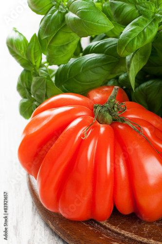 Fresh tomato with basil om old wooden board. photo